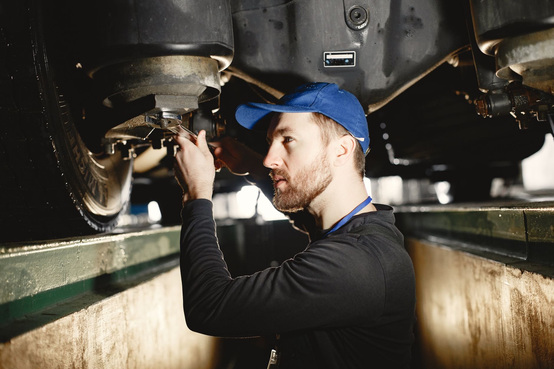 Auto mechanic working diligently on vehicle in workshop setting. Expertise in repair and maintenance.